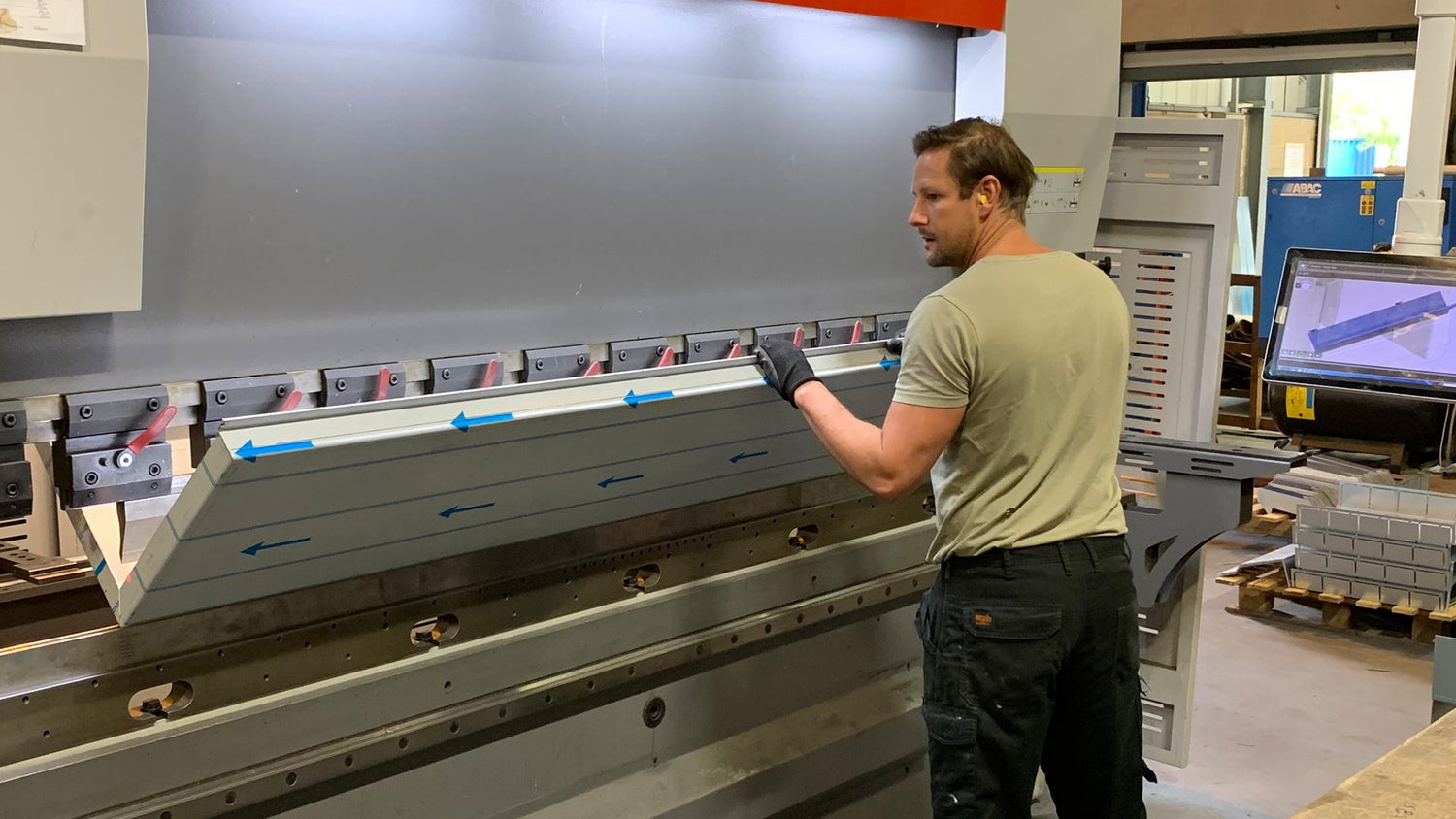 Sheet metal worker operating a CNC press brake machine in the UK